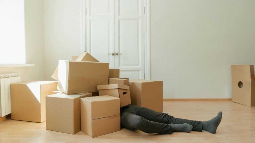a man covered in moving boxes, thinking about how to cut stress when planning a move