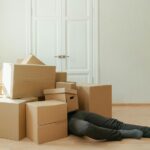 a man covered in moving boxes, thinking about how to cut stress when planning a move