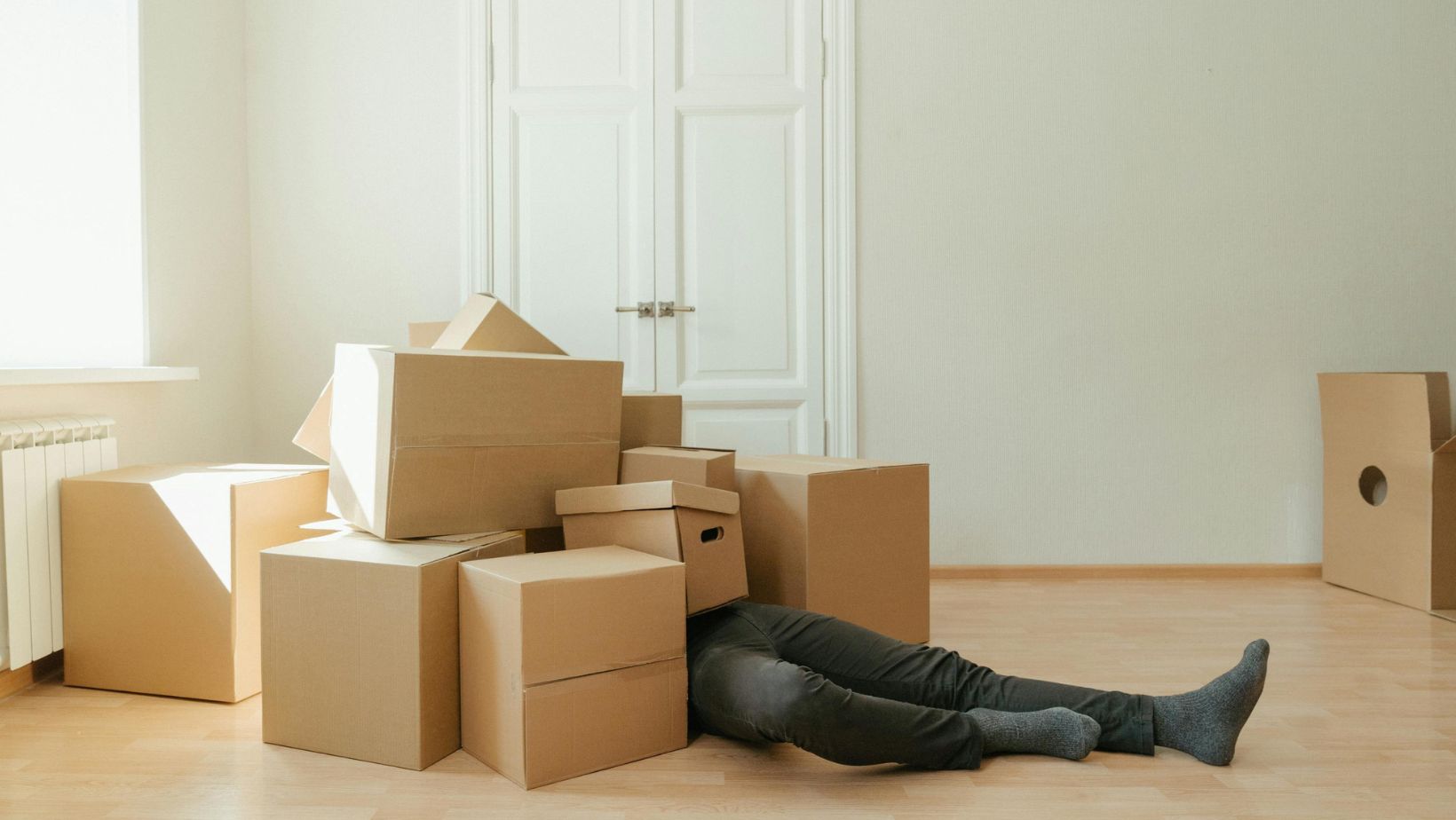 a man covered in moving boxes, thinking about how to cut stress when planning a move